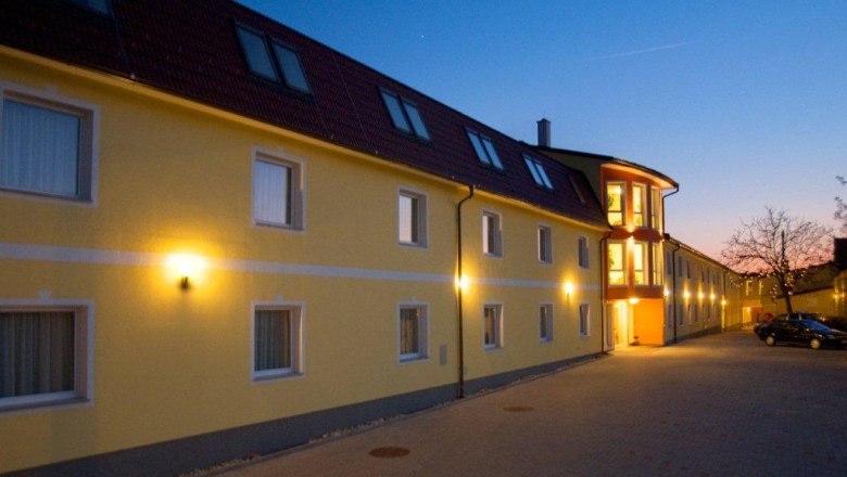 Hotel Radlinger, © Hotel Radlinger Yellow hotel building at dusk with illuminated windows and entrance.