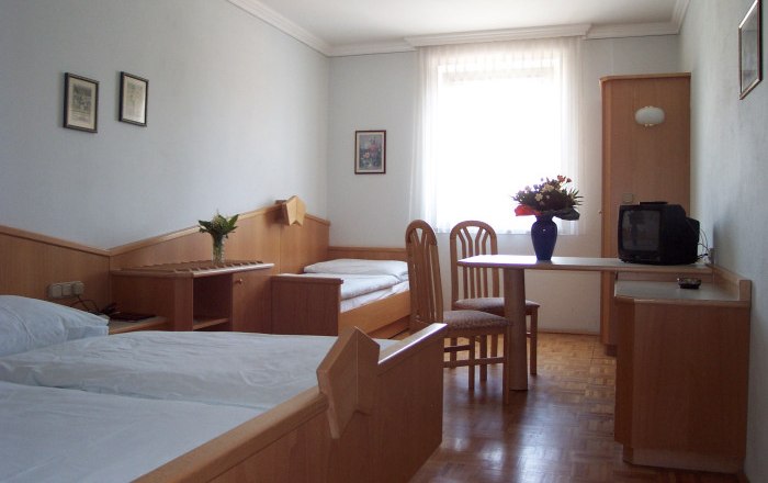 Hotel zum Goldenen Stern, © Familie Graf A simply furnished hotel room with two beds, a table, chairs and a small TV.