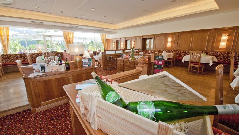 Restaurant at the Gartenhotel Pfeffel, © Alexander Pfeffel Interior view of an elegant restaurant with wooden furniture and bottles of wine.