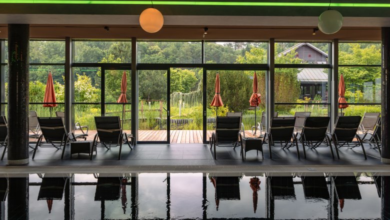 Hotel & Spa Linsberg Asia, © Niederösterreich Werbung / Maximilian Pawlikowsky Interior view of a spa with sun loungers and a view of a garden through large windows.