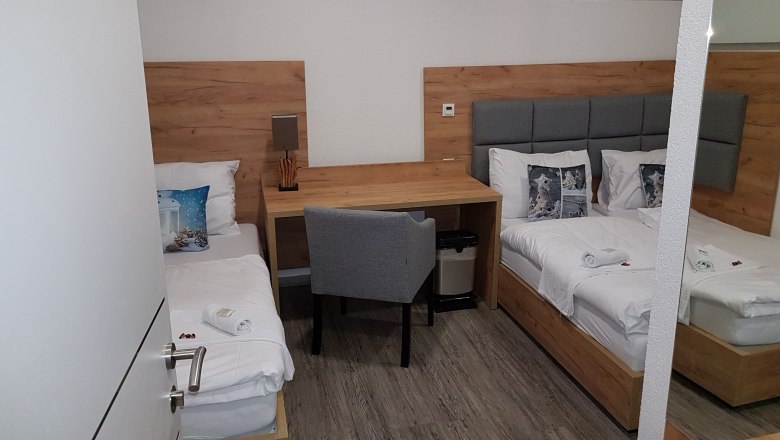 Triple room, © Konrad Brandl Triple room with two single beds, desk and chair.