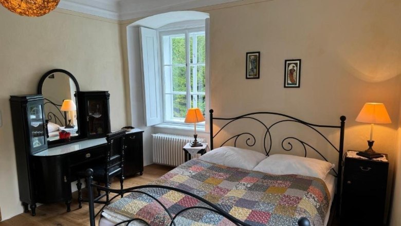 Guest room, © Andrea Schubert Cozy guest room with double bed, antique dressing table and warm light.