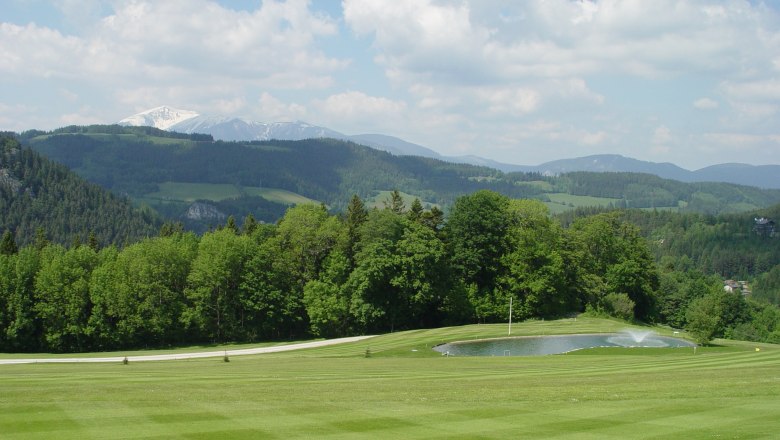 Semmering Golf Club, © Golfclub Semmering Green golf course landscape with pond and wooded hills in the background.