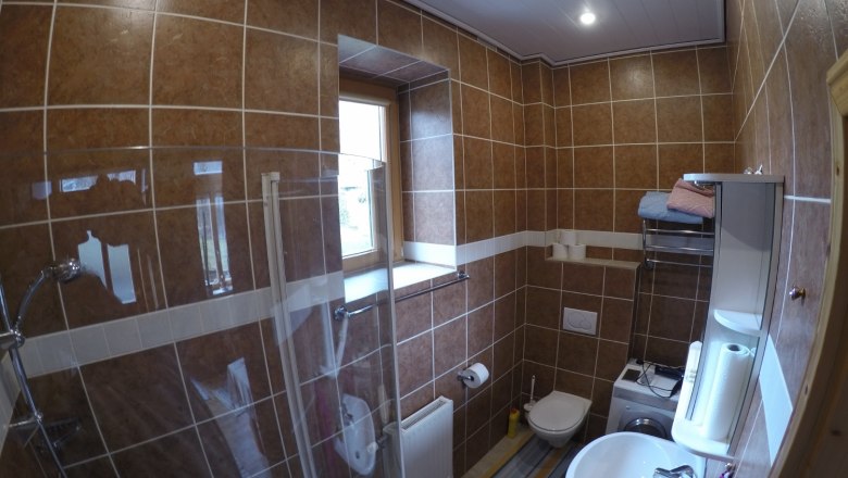Bathroom/WC Apartment 2, © dmgrauszer Bathroom with brown tiles, shower, washbasin, toilet and washing machine.