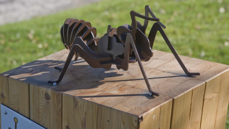 Corona's ant trail, © Martin Weiner Metal sculpture of an ant on a wooden block outdoors.