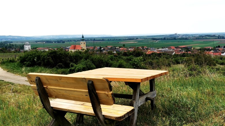 Rest area at the Weinviertelwarte, © Weinstraße Weinviertel Wooden bench with table on a hill with a view of Röschitz and the surrounding countryside.