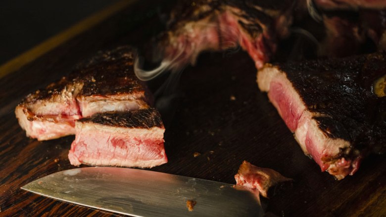 Every steak is a precision landing, © Niederösterreich Werbung/Michael Reidinger Close-up of sliced steak on a wooden board with a knife next to it.
