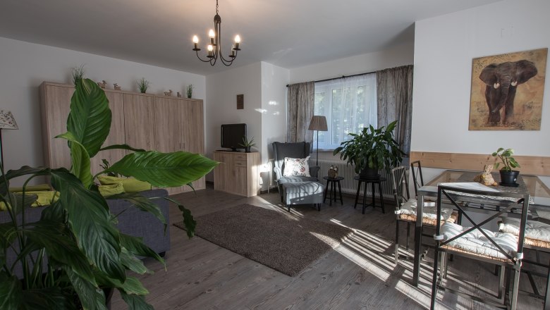 Vacation apartment, © A. Dirnbauer Cozy living room with plants, dining table and sofa.