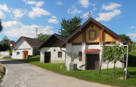 Wine cellar lane Zwingendorf, © Adolf Schmid Traditional wine cellars in a rural setting with blue skies and clouds.