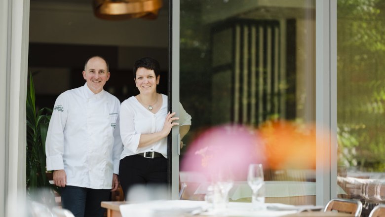 Landlords Roland and Ruth Krammer, © Niederösterreich Werbung/Michael Reidinger A man in chef's clothes and a woman stand smiling in an open doorway of a restaurant.