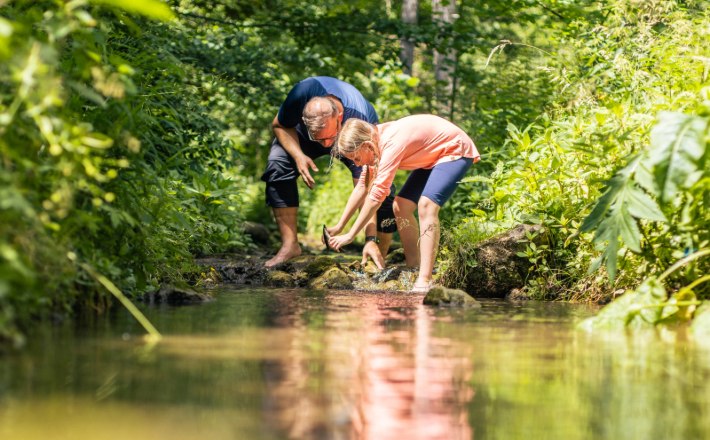Johannesbachklamm_(c)_Fülöp, © (c)Fülöp Two people bend over a stream in a green forest.