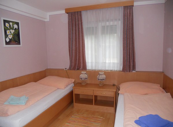 Zum grünen Baum Gasthof Schreiblehner, © Gasthof zum grünen Baum, Schreiblehner A simply furnished room with two single beds, a window with curtains and a small table with two lamps.