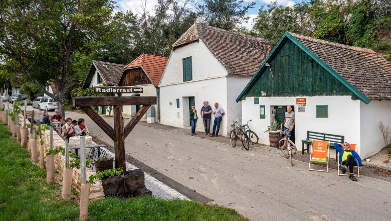 Cellar feel-good place in Mailberg, © Initiative Pulkautal / P. Mödl Weinkellerstraße in Mailberg with people, bicycles and a sign 'Radlerrast'.