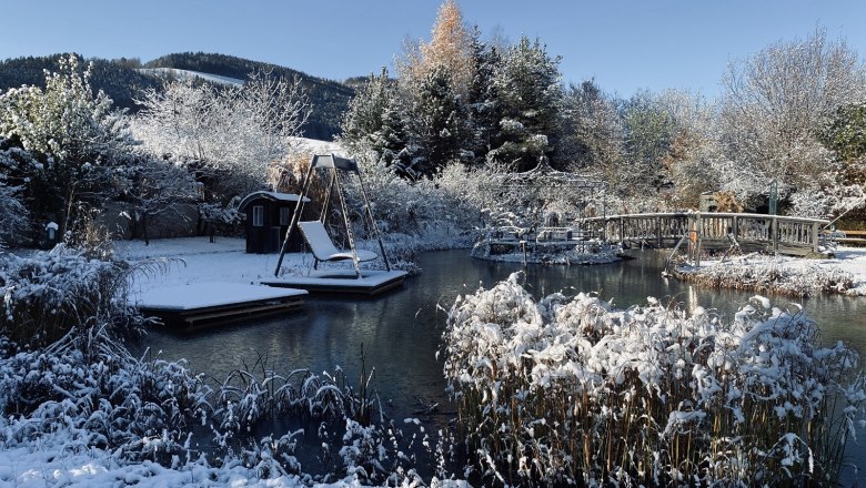 Paradiesgartl in winter, © Peter Pichler Snow-covered garden with pond, bridge and swing in winter.