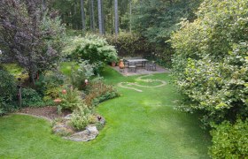 insight-into-the-garden, © Dagmar Scheucher A well-kept garden with lawn, trees and a seating area on a terrace.