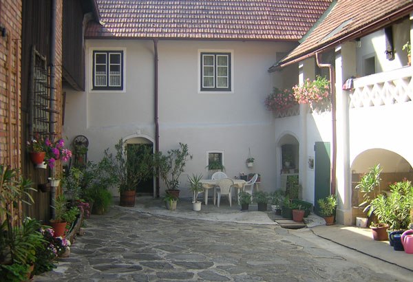 House Stierschneider, © Familie Stierschneider Inner courtyard of a traditional house with plants and seating area.