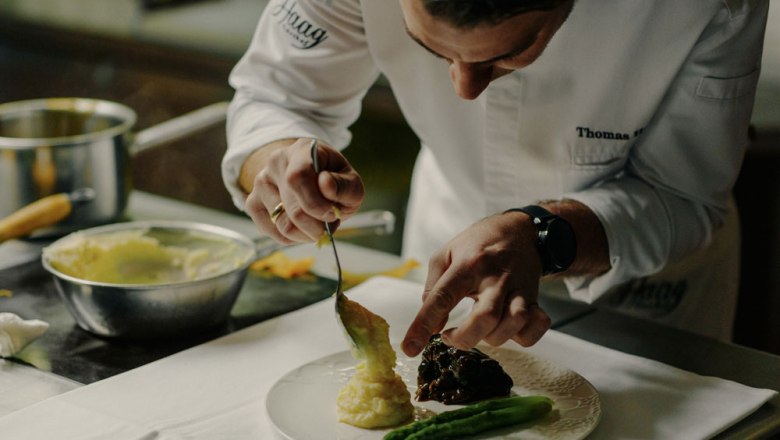 Thomas Haag works his magic in the kitchen, © Niederösterreich Werbung/Julius Hirtzberger A chef prepares a dish of asparagus and mashed potatoes on a plate.