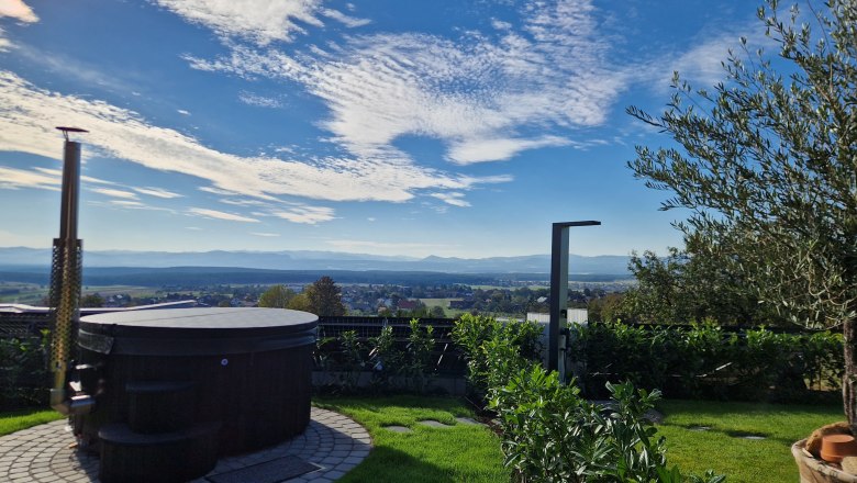 Hot Tub Johannesbachklamm Chalet, © Johannesbachklamm Chalet A round whirlpool in the garden with a view of a vast landscape and blue sky.