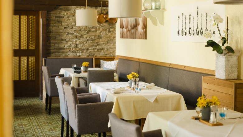 Good food, good wine, inviting ambience, © Niederösterreich Werbung/Michael Reidinger Inviting restaurant with laid tables, gray chairs and decorative elements on the walls.