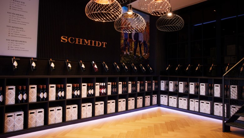 Self-service store, © Ben Leitern Wine rack with bottles and boxes in a stylish room with the lettering 'Schmidt'.