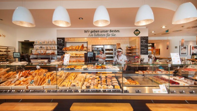 Café Haubiversum, © Haubis GmbH Interior view of a bakery with a counter full of baked goods and two employees.