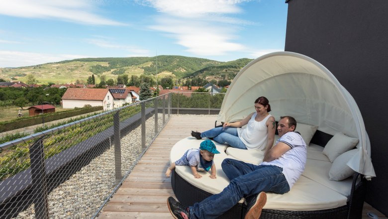 Lounge furniture on the terrace with a view, © KASTNER NEW MEDIA - kastner.tv Family relaxing on a terrace with a view of the rural landscape.