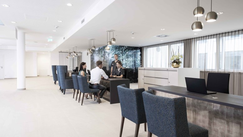 Reception, © NMC Modern reception with people sitting at a table and talking.