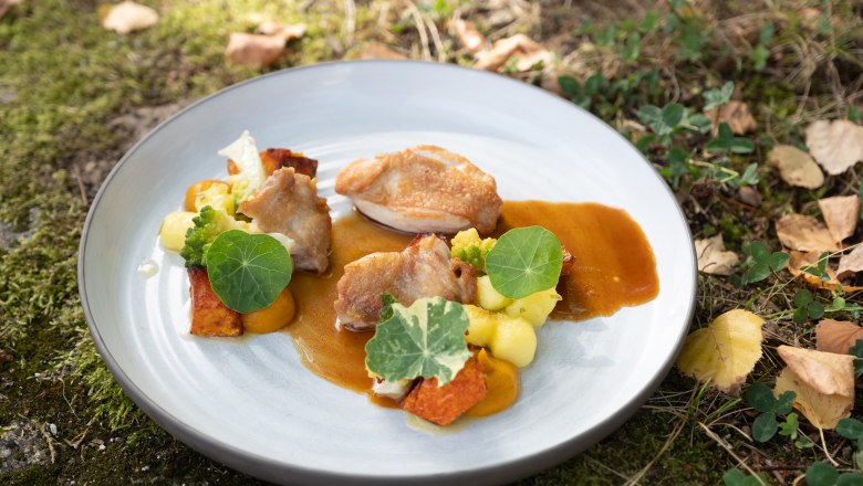 Poussin with pumpkin, © Franz Kuben A plate of poussin, pumpkin and green leaves, arranged in a meadow.