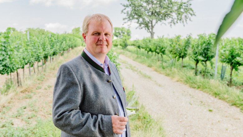 Ludwig Hofbauer, © Leonardo Ramirez Man in traditional clothing with a wine glass in a vineyard.
