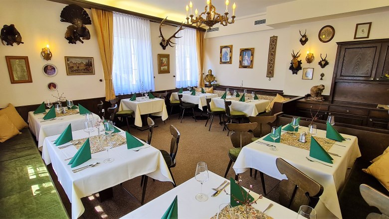 Hunting parlor, © Hotel Kaiser Franz Josef A traditionally decorated dining room with hunting trophies on the walls and laid tables.