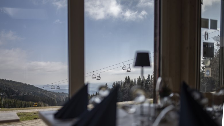 Alpengasthof Enzian, © Thomas Gobauer View from a window of a mountain landscape with chair lift and forest.