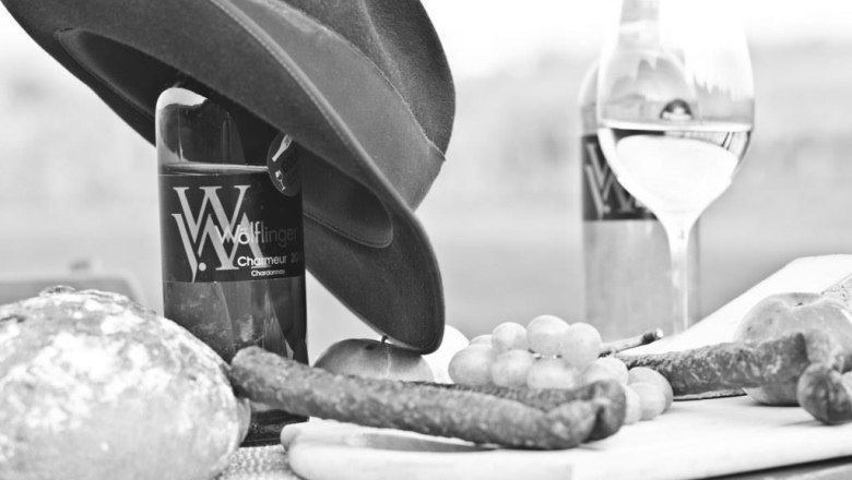 Viticulture Wölflinger, © Fotohaus Hans Krist Black and white picture of wine bottles, bread, sausage and grapes on a table.