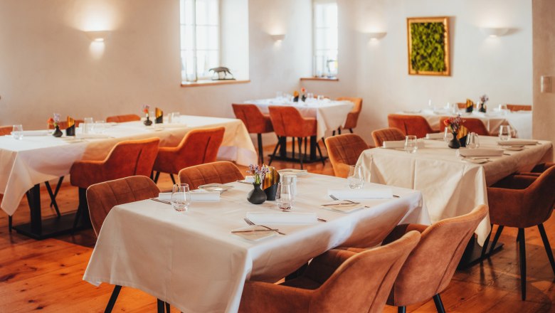 Restaurant, © Niederösterreich Werbung / Daniela Führer Elegant dining room with laid tables and brown chairs.
