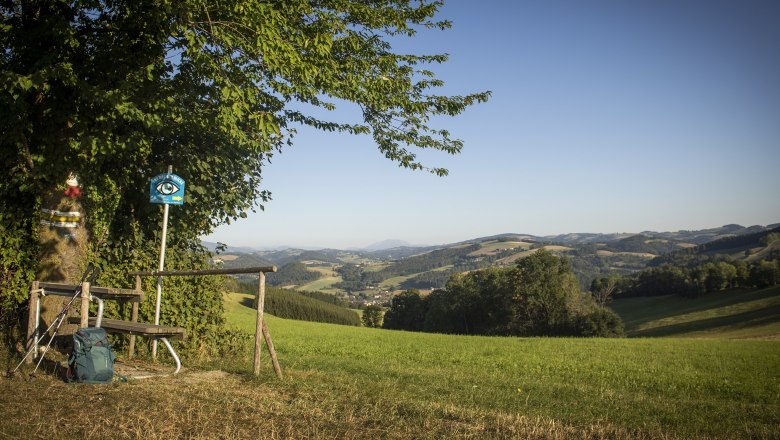 View of the Schneeberg, © Gemeinde Bad Schönau, Stefan Knittl Landscape with bench, walking stick and rucksack in the foreground, hills and mountains in the background.