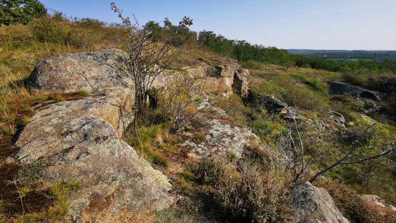 Rock formations and magnificent views, © Weinstraße Weinviertel Rocky landscape with sparse vegetation and blue sky.