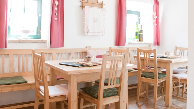 Wine tavern zum Baumbart, © Bernd Baumgartner Cozy dining room with wooden furniture, red curtains and decoration.