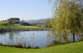Lengenfeld Golf Club, © Golfclub Lengenfeld Landscape with golf course, pond and buildings in the background.