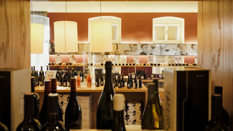 Wine bar on the second floor, © Niederösterreich Werbung/Michael Reidinger Interior view of a wine shop with wine bottles and decorative lamps.