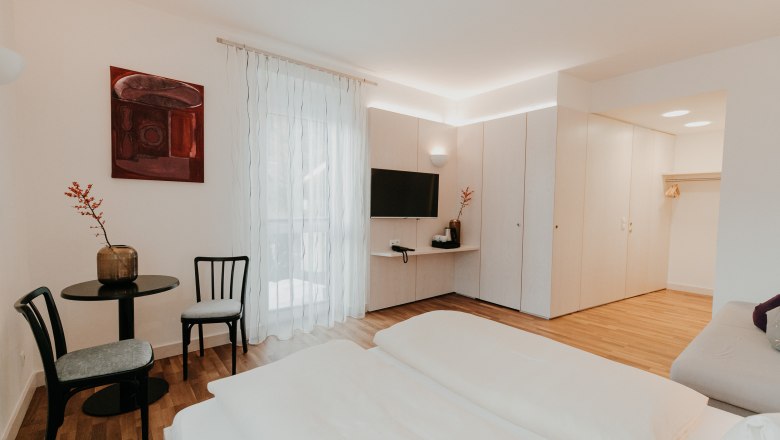 Newly renovated rooms, © Der Löffler - Nicole Seiser Modern, bright hotel room with double bed, TV, table and chairs, wardrobe and decorative picture on the wall.