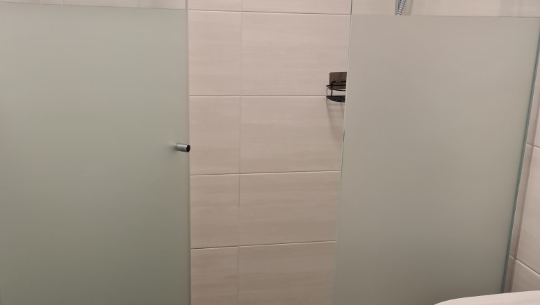 TDR-GasthofKirchenwirth shower, © Josef Burger Modern shower with glass walls and shower head in a bathroom.