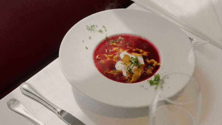 Beet soup, © Niederösterreich Werbung/Julius Hirtzberger A plate of beetroot soup, garnished with cream and herbs, on a laid table.