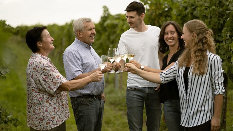 waltz-johann-20, © Weinbau Johann Walzer Five people clink glasses in a vineyard.
