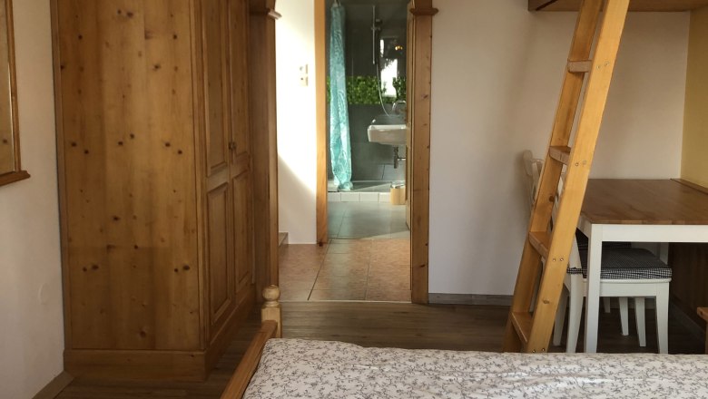 Room passage vacation at the Jauerling, © Romana Wiener Interior view of a room with wooden furniture and a passageway to a bathroom.