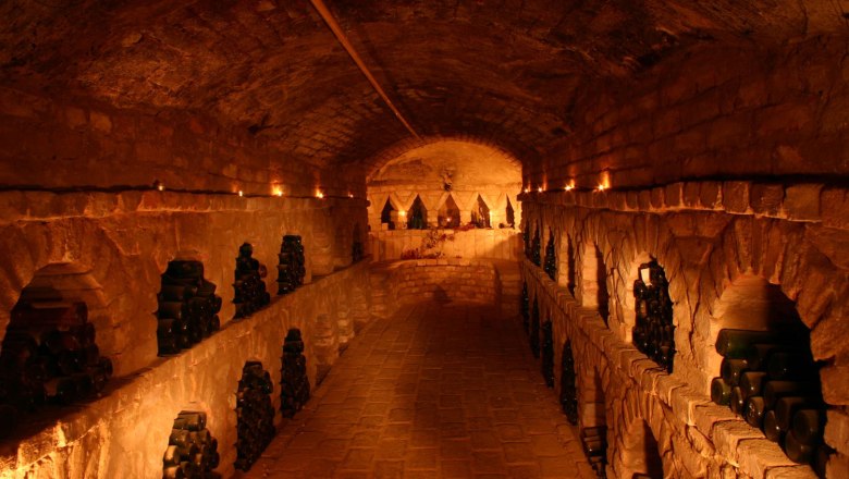 Labyrinth cellar, © Umschaid An atmospherically lit wine cellar with bottles stacked in niches along the walls.