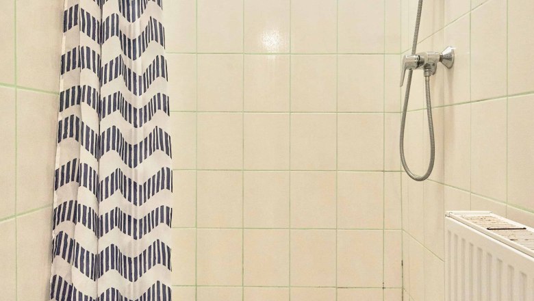 Top 2 - Bathroom, © VP FeWo OG Shower with shower curtain and hand shower in a tiled bathroom.