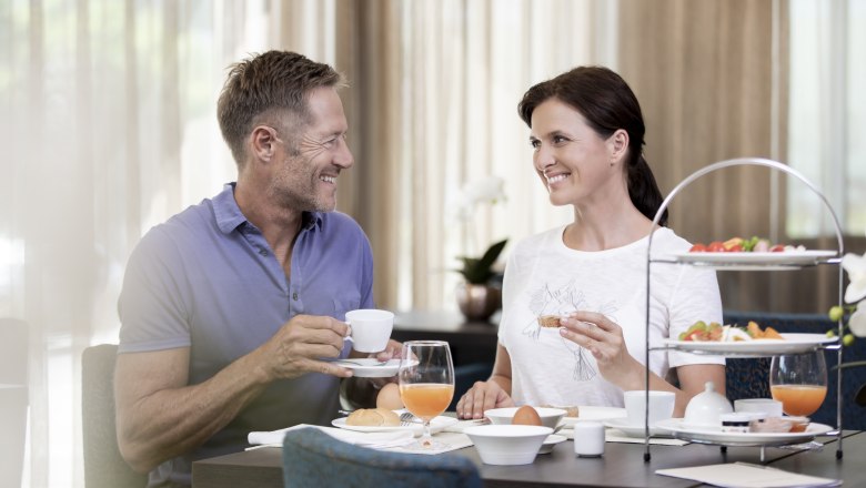 Breakfast couple, © NMC A smiling couple having breakfast at a table with coffee and orange juice.