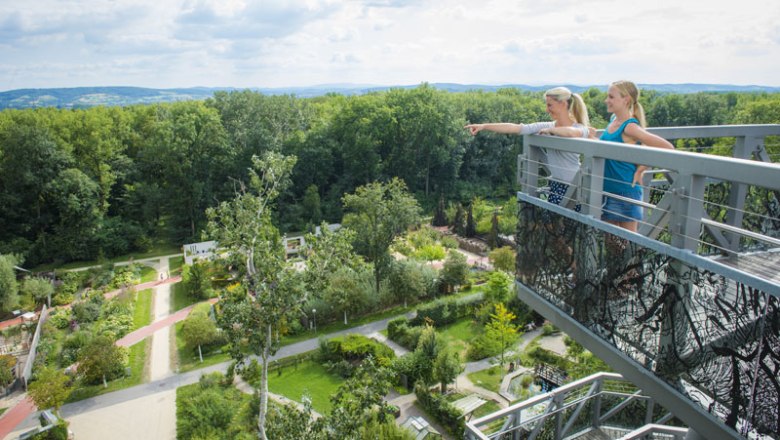TD-DIE-GARTEN-TULLN-Tree-top walk-Robert-Herbst, © Robert Herbst Two women stand on a lookout tower and look out over a green garden with trees and paths.