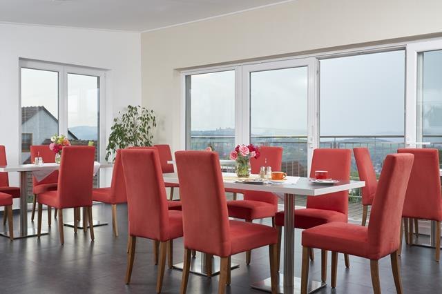 Wood hay breakfast room2, © Philipp Monihart Breakfast room with red chairs, wooden furniture and coffee machine.