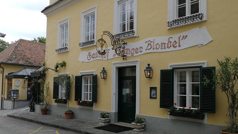 Restaurant Singer Blondel, © Roman Zöchlinger Yellow building with the inscription 'Gasthof Sänger Blondel', windows with green shutters and flower boxes.