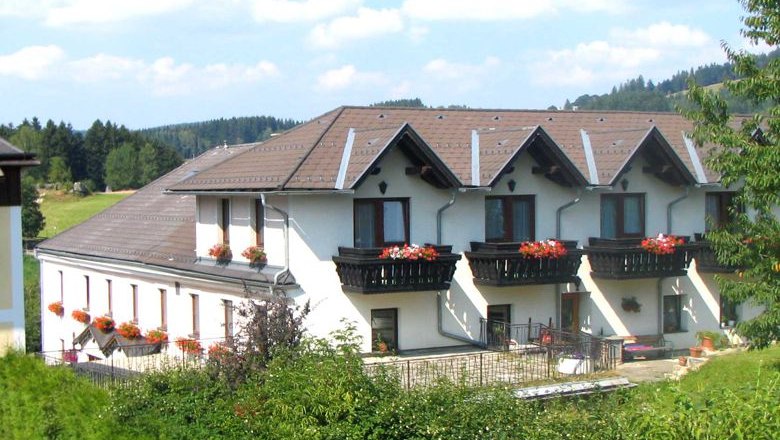 Angerhof, © Buchinger A large, white building with brown roofs and balconies with flowers.